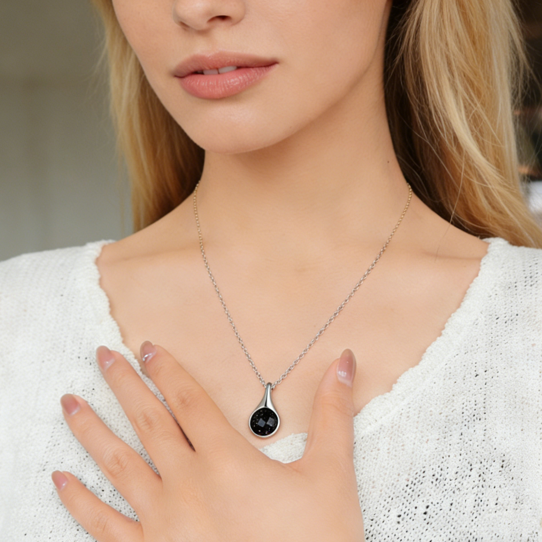 Woman wearing a silver necklace with a black pendant